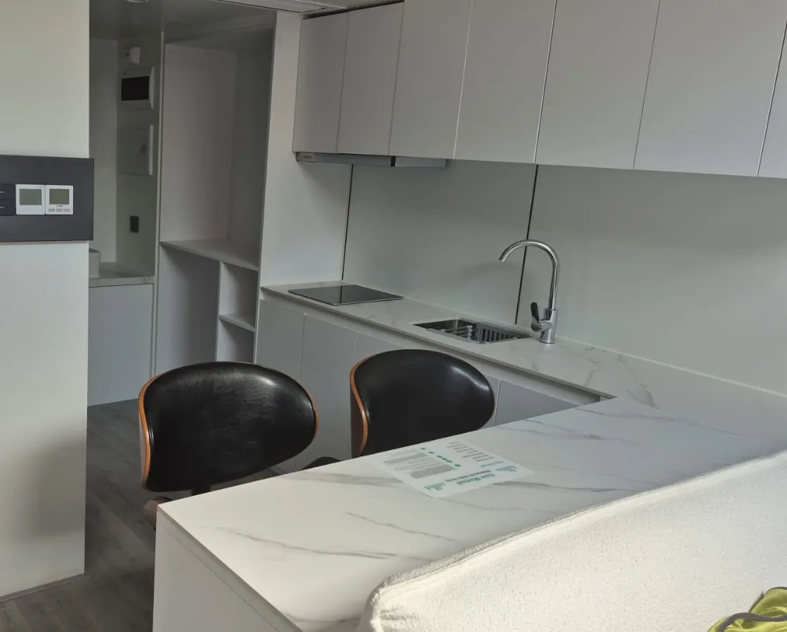 White fitted kitchen with a breakfast bar and stools