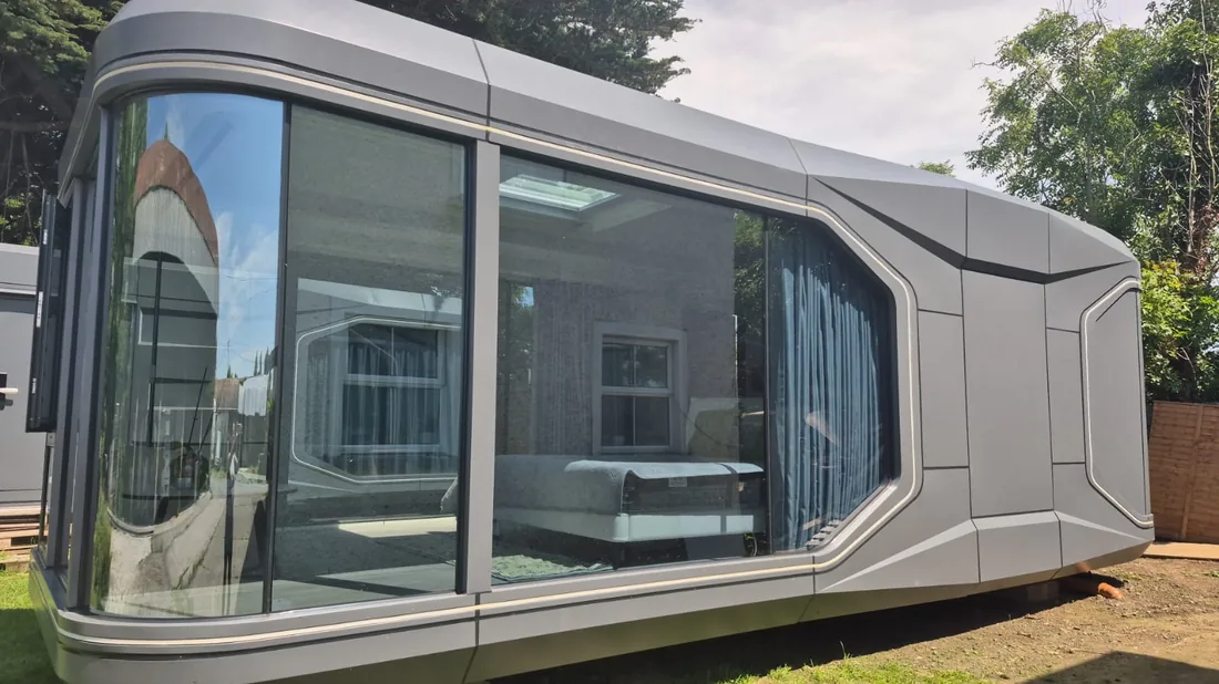 A long grey pod with a glazed corner showing the bedroom inside